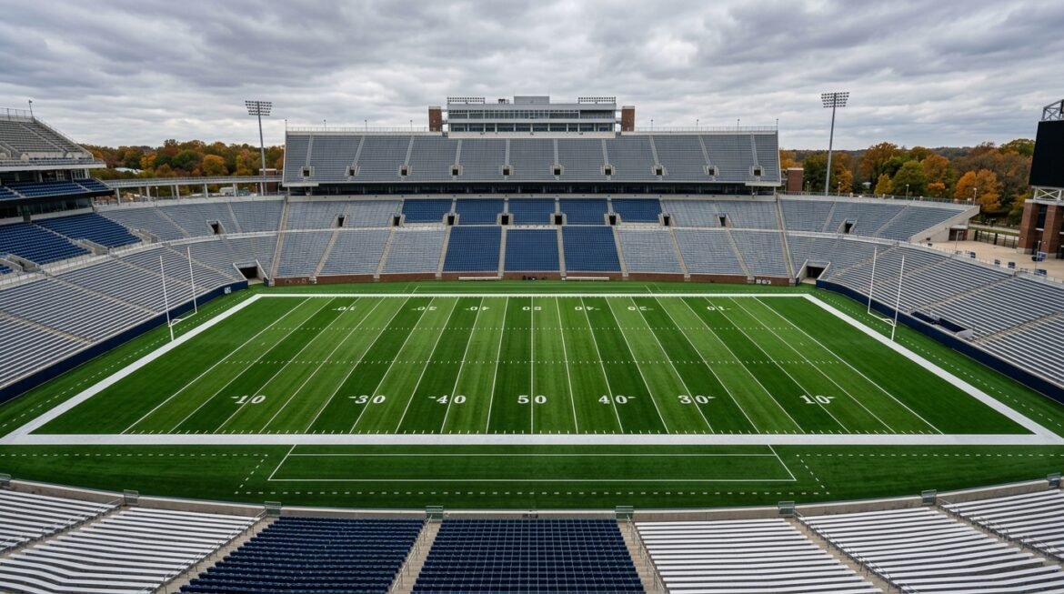An empty college football stadium field under an overcast sky.